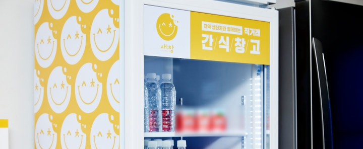 노랑 새참 간판을 단 유리문 음료 냉장고 윗부분과 스마일 패턴 벽면