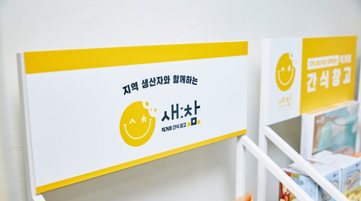 노랑 스마일 심볼과 새:참 워드마크가 들어간 흰 간판